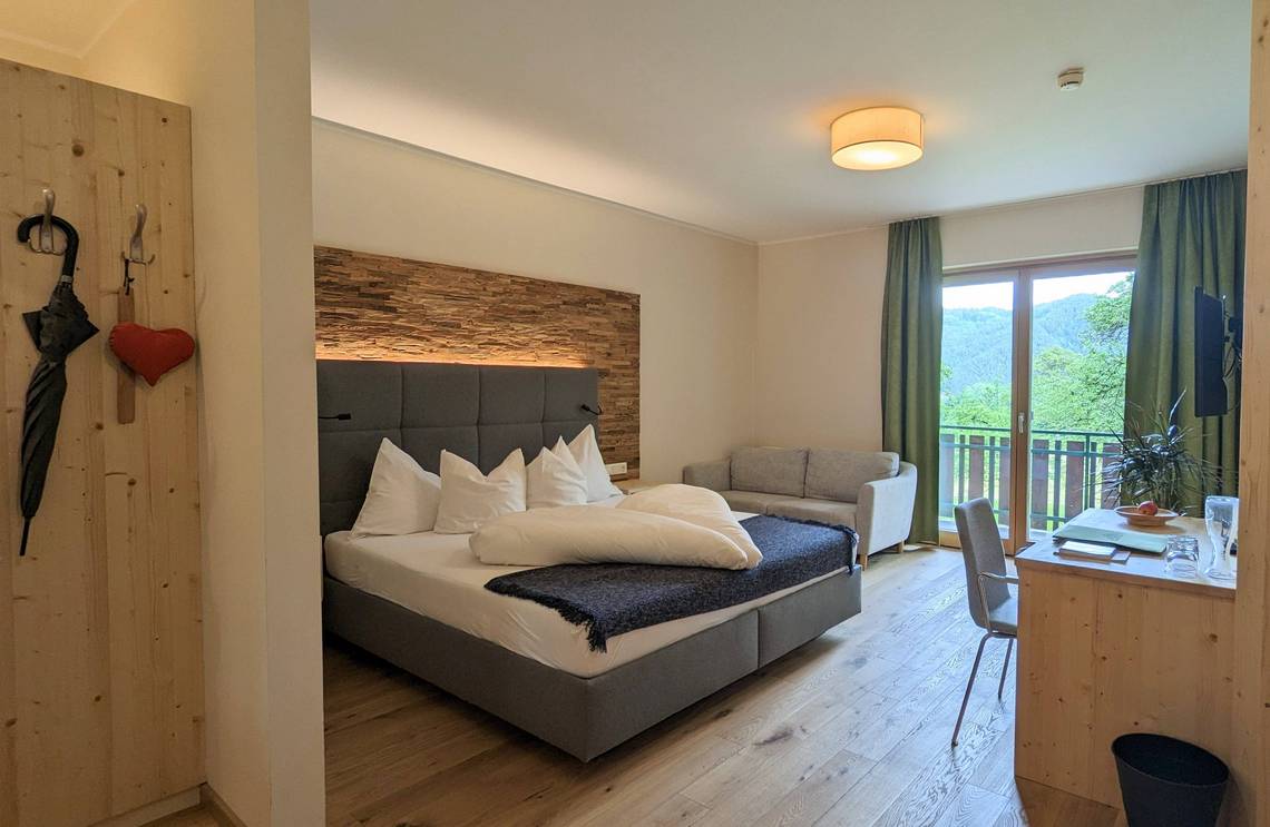 Zimmer Molzbach mit Doppelbett, Schreibtisch, Sofa und Balkon im Naturhotel Molzbachhof.