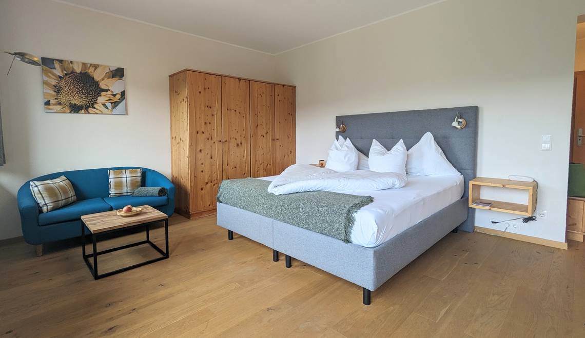 Zimmer Paradiesgartl mit Doppelbett, Schrank, Sofa und Tisch im Naturhotel Molzbachhof.