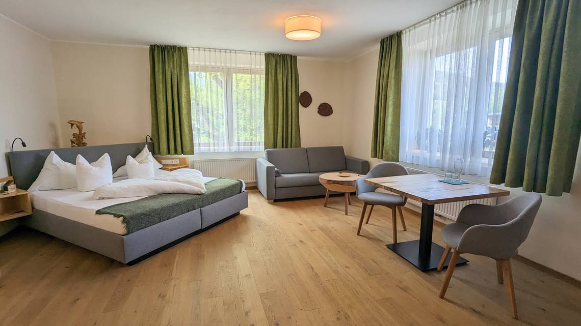 Zimmer Ebenfeld mit Doppelbett, Sofa und Sitzecke im Naturhotel Molzbachhof.